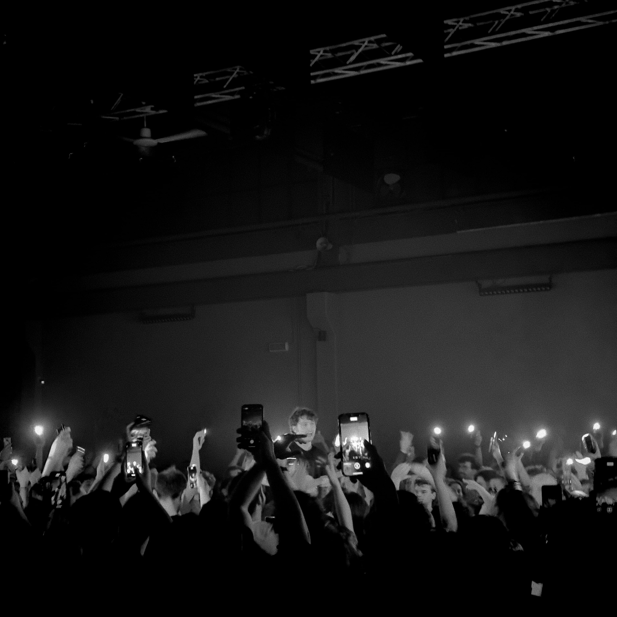 A concert crowd holding up phone lights, in black and white.