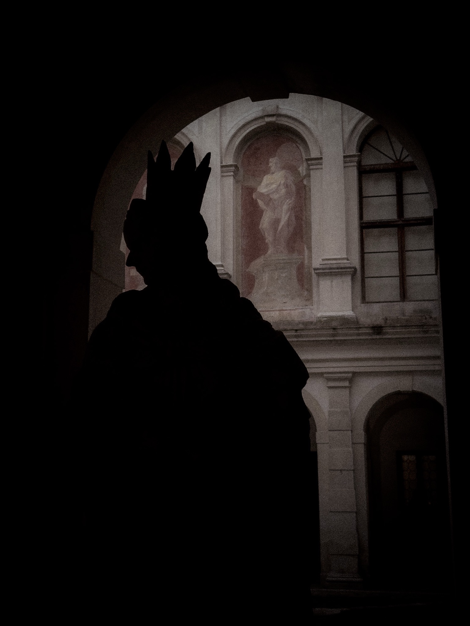 Dark silhouette of a statue beneath an arch.