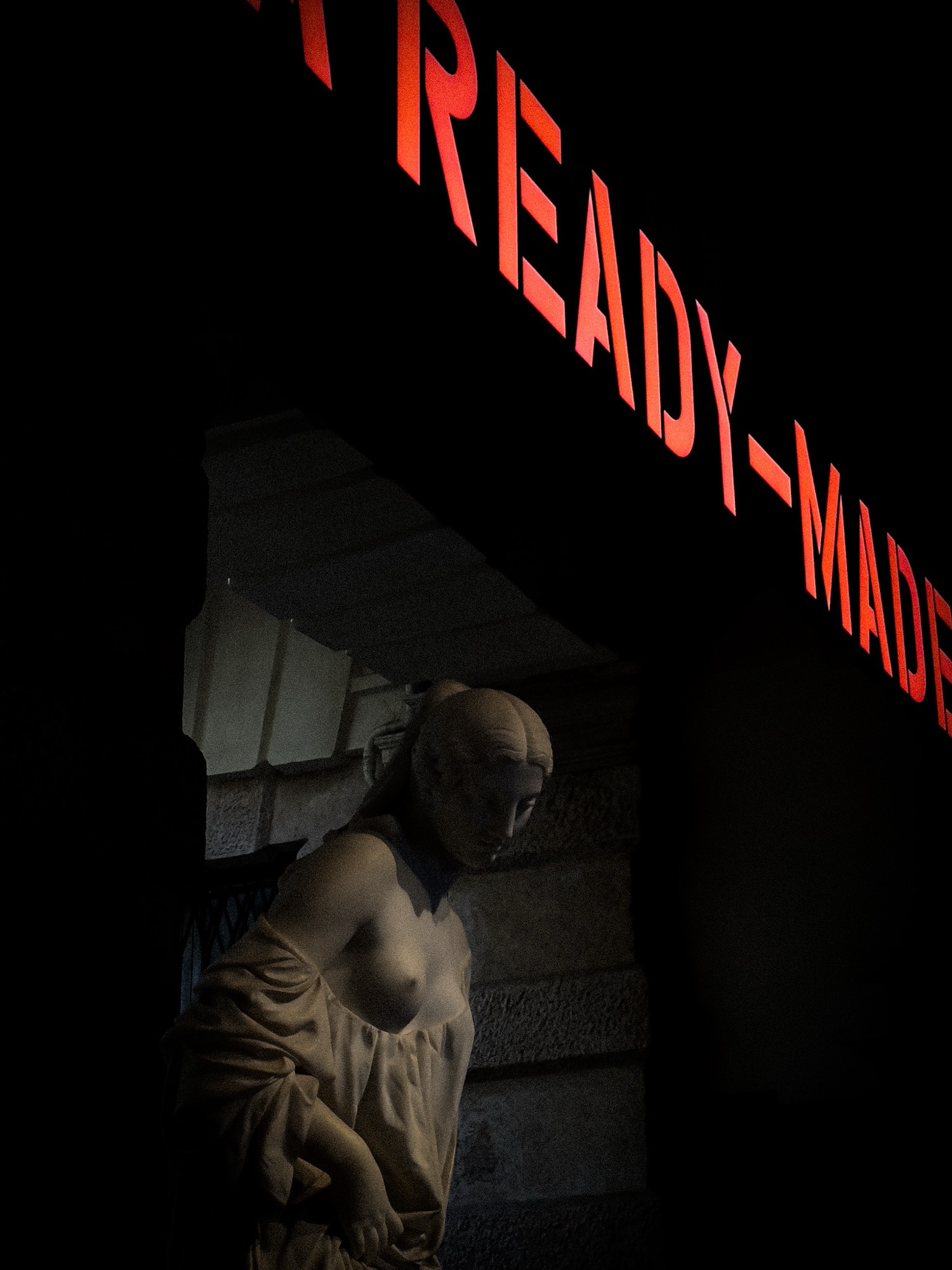 An illuminated statue beneath red lettering on black.