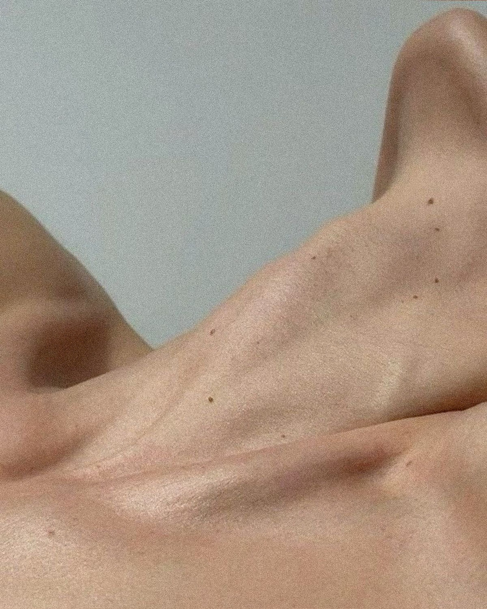 Close-up of shoulders and collarbones, crossed by light.