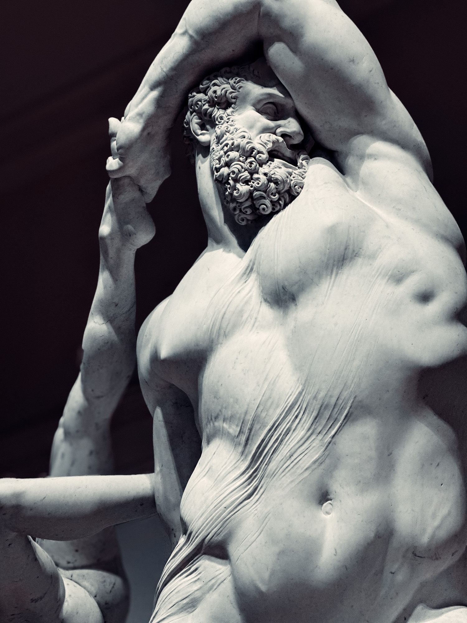 Detail of a marble statue with one arm raised.
